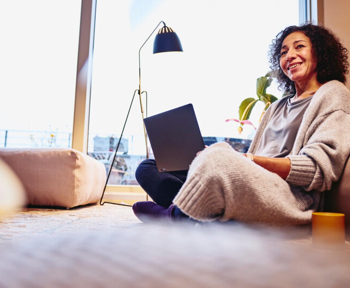 a woman sitting down on the couch with her laptop