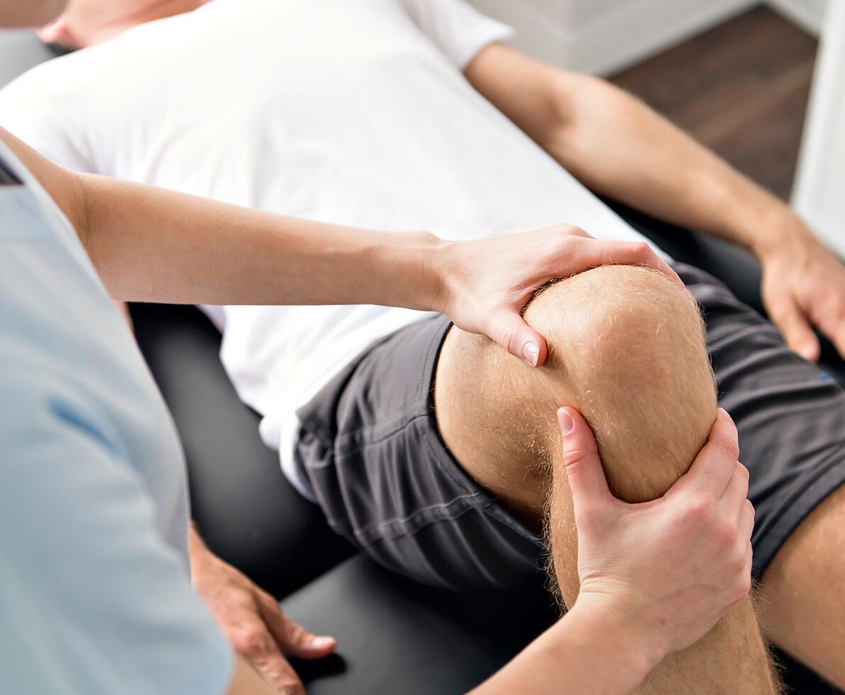 physio fixing a man's leg by bending his knee