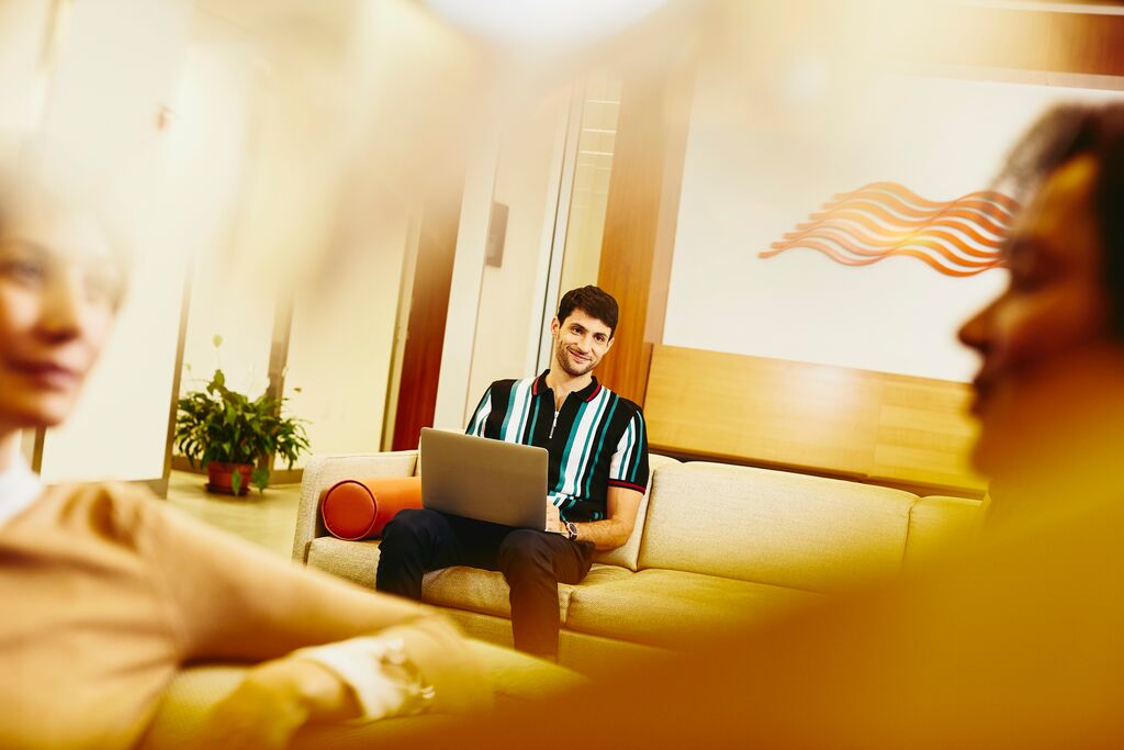 A photo of a smiling man using his laptop to submit their cv