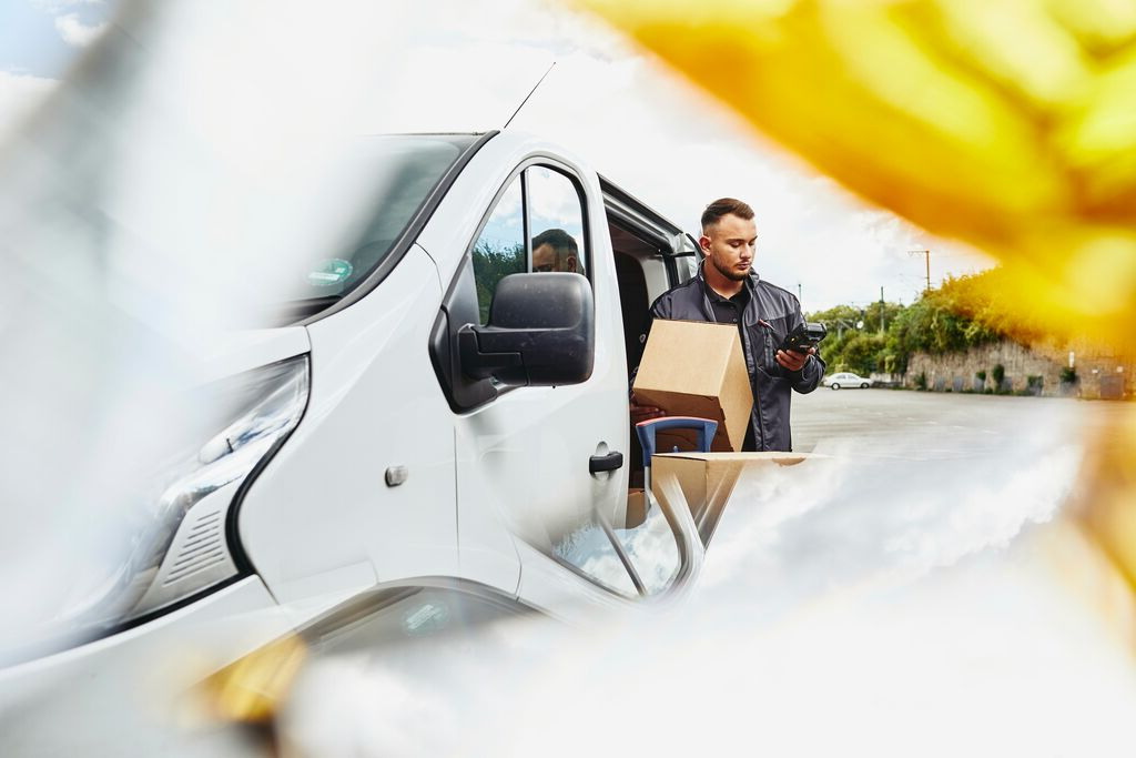 A photo of a man driving a van off to deliver packages