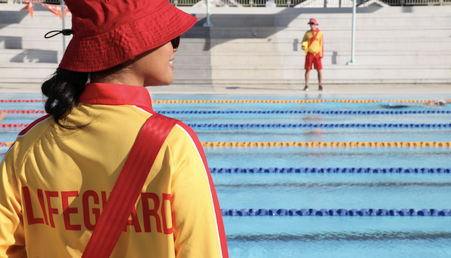 two female lifeguards standing on the side of the pool