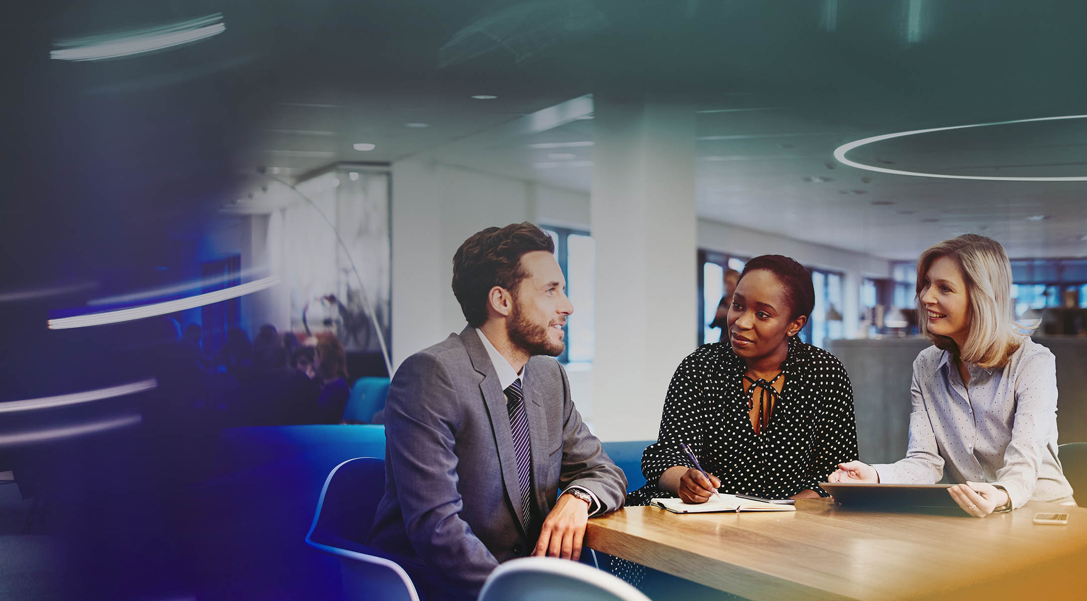 three colleagues sitting at a table in an office having a meeting