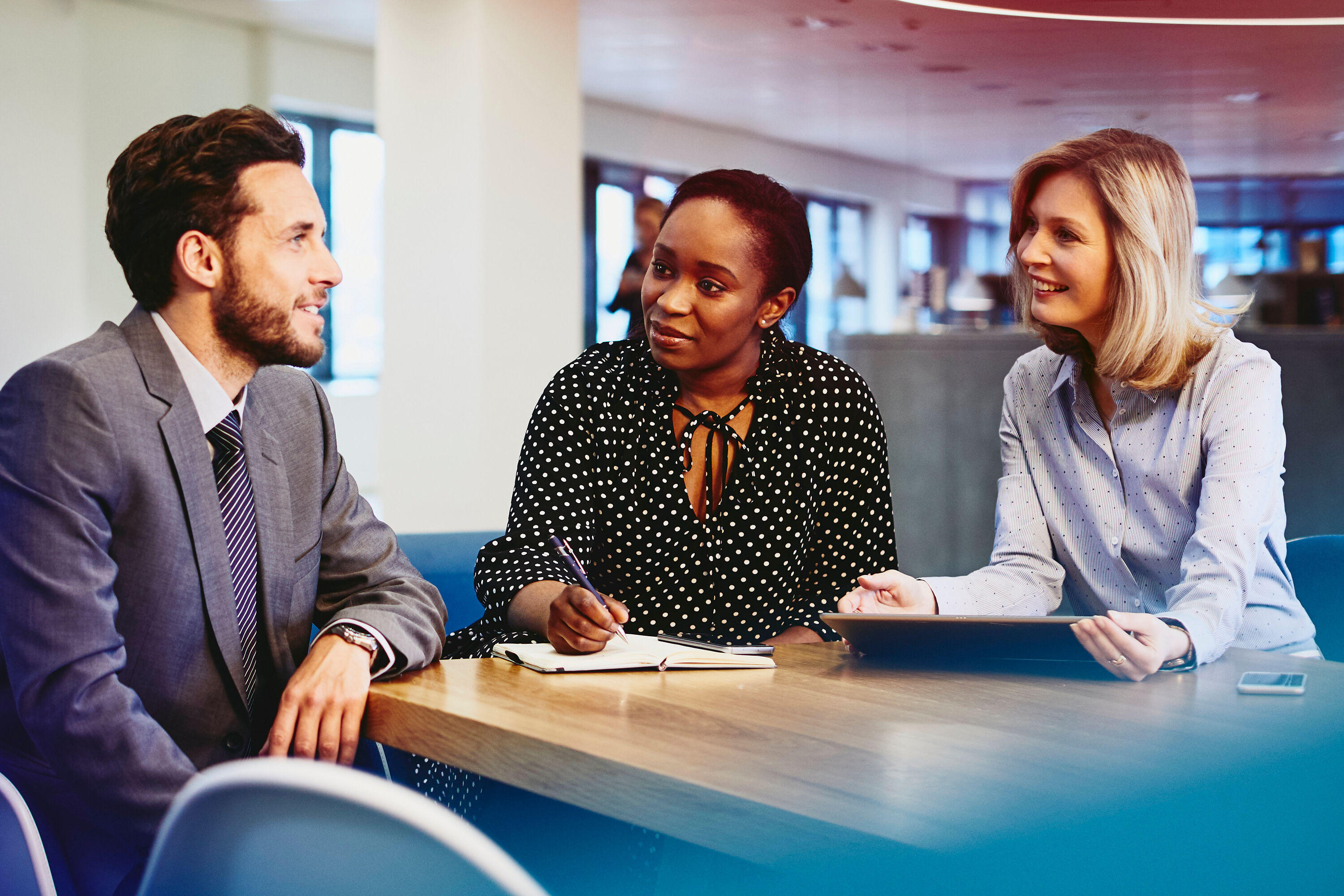 an image of three colleagues chatting while wearing business suits