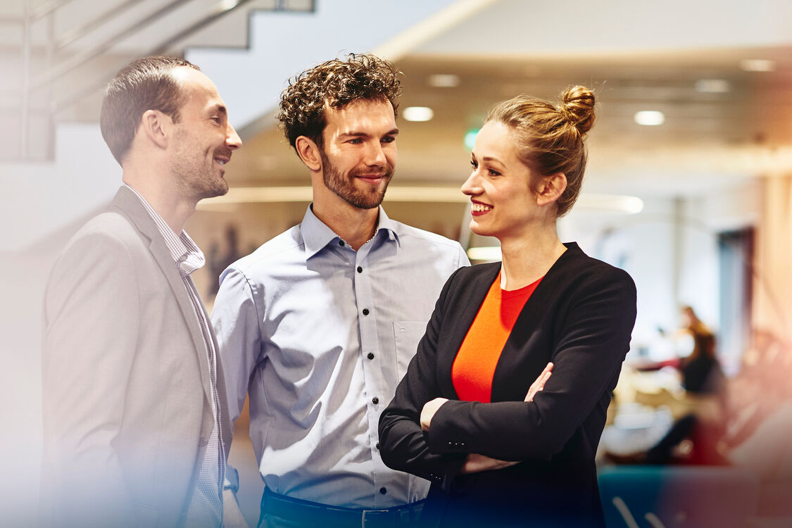 an image of three colleagues chatting while wearing business suits