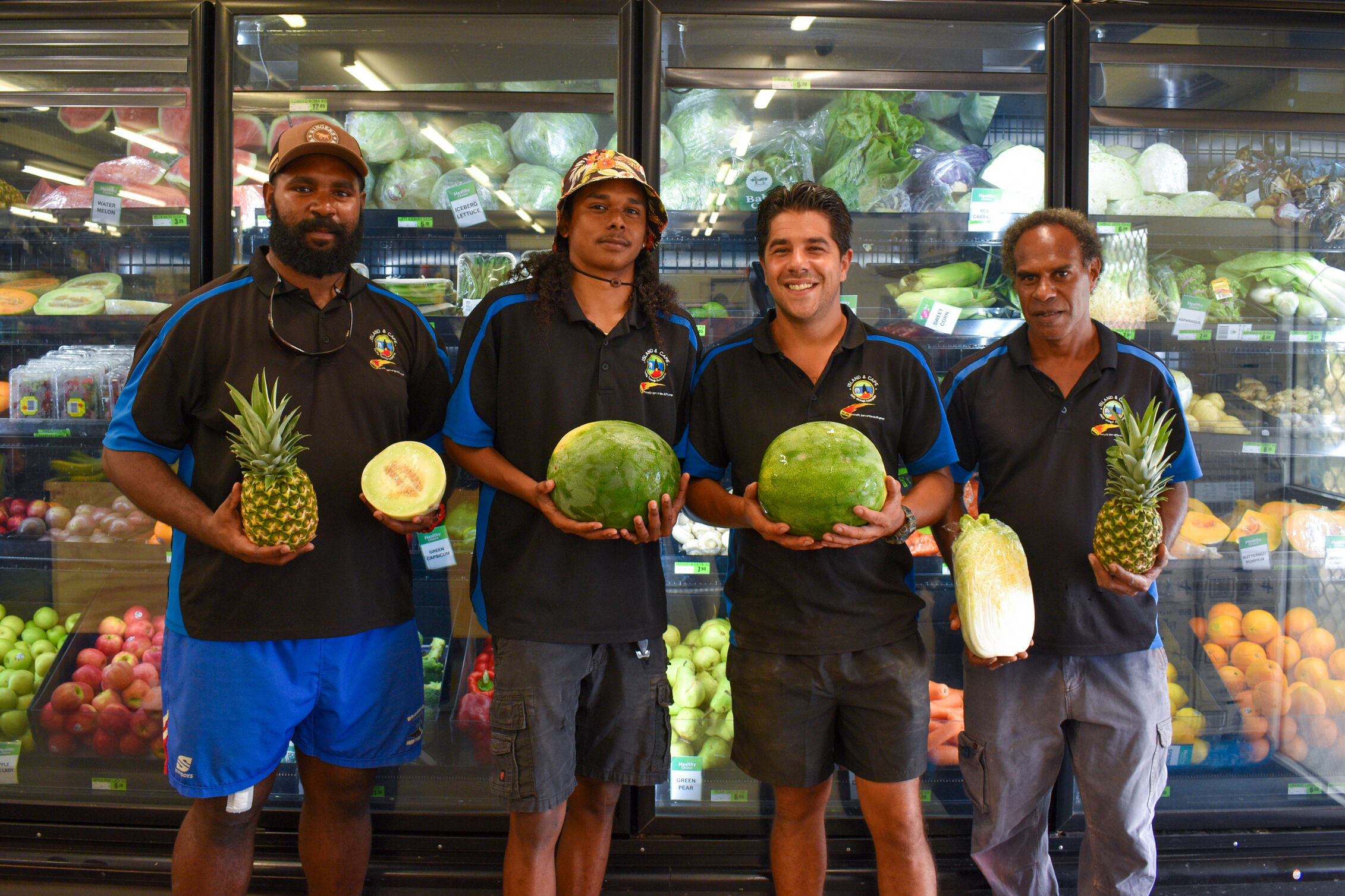 an image of 4 men smiling while holding fruits