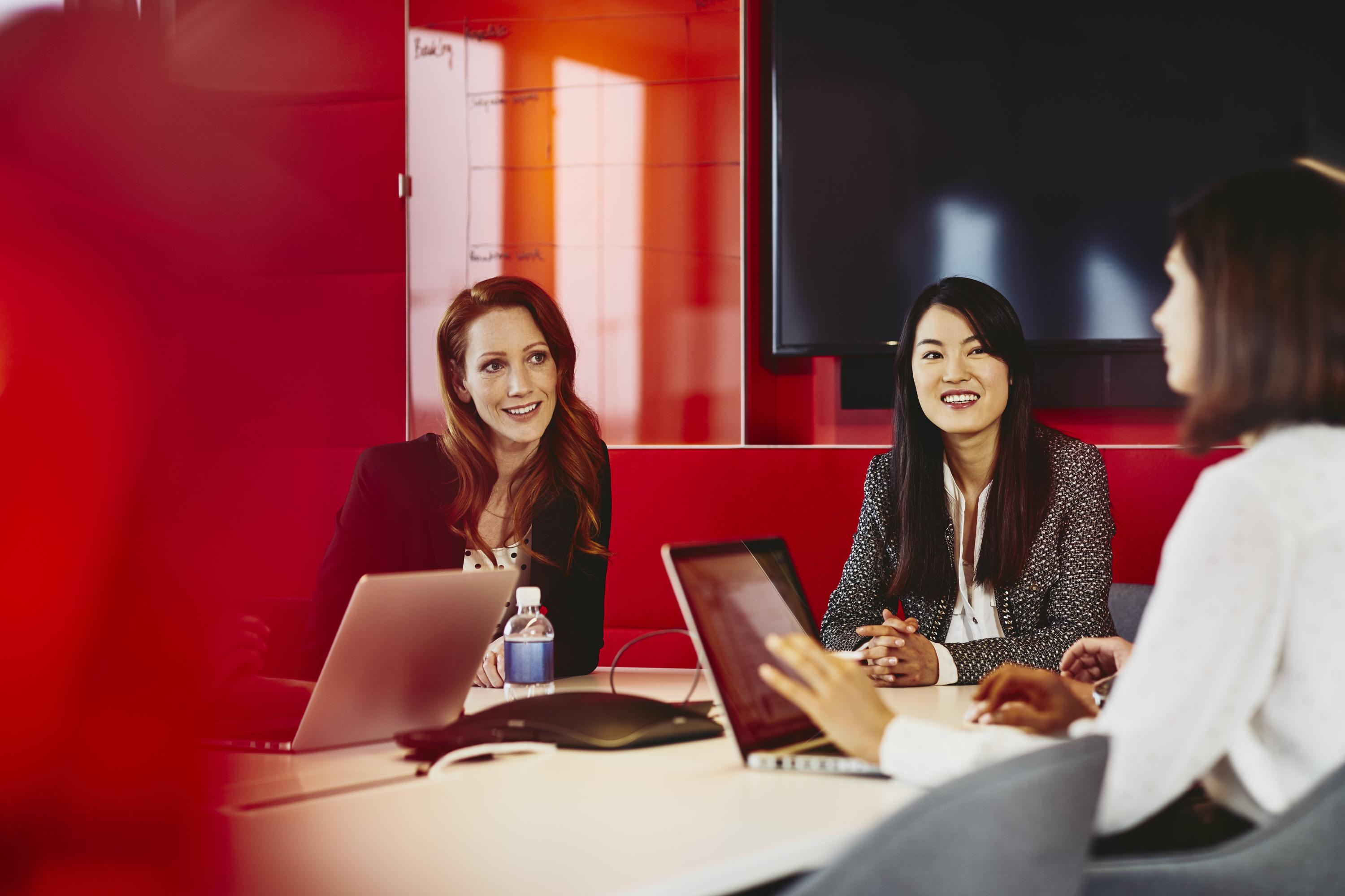 Group of business women having a meeting. Primary color: red.