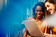 Two women looking into a laptop and smiling