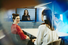 Two business women and a man in an office having a Hangout