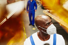 A photo of a man wearing a mask working in the construction sector