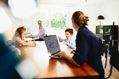 Woman working from home with her family in the background