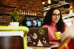 Woman holding a cup smiling at her colleague