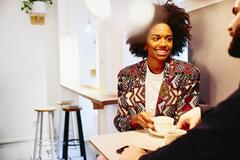 Woman talking to a man while holding a cup of coffee