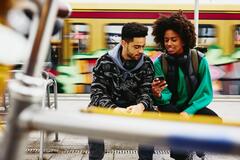 A photo of a man and a woman working remotely by the train platform
