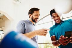 Two men smiling while looking at a phone