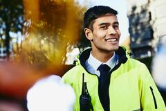 Smiling man looking away wearing yellow jacket and walkie-talkie