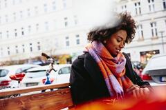 Woman looking at watch while sitting on a bench outside.