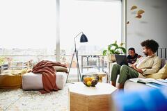 Man sitting on couch with his laptop, looking serious at a kid