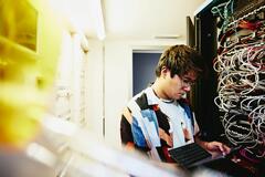 Man looking at a tablet standing in a servers room.