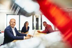 Man working on his laptop, in the background two women having fun and laughing