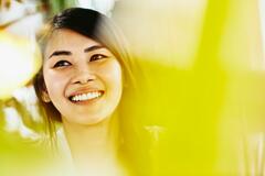 woman with dark coloured haired looking up smiling with a yellow filter