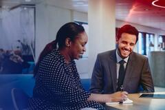 two women and a man in the middle talking in an office space
