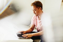 a man typing in his laptop wearing a pink polo shirt