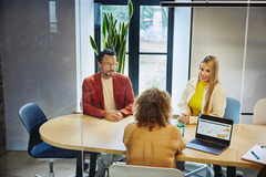 an image of three people in a meeting room discussing 