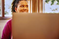 an illustration of a woman smiling while looking to the right with a laptop in front of her