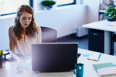 woman sitting at a desk behind a laptop
