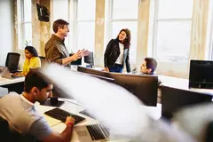group of smiling colleagues in an office having a conversation