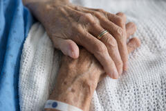 a patient with their hands clasped together in a hospital bed