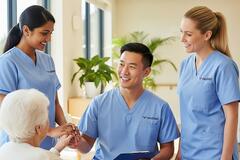 three smiling aged care nurses in an aged care facility with one of their residents