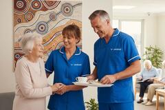 two aged care workers smiling with an older lady