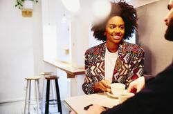 Woman talking to a man while holding a cup of coffee