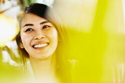 woman with dark coloured haired looking up smiling with a yellow filter
