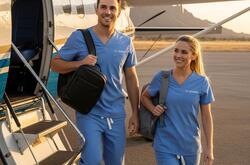 two travel nurses wearing scrubs exiting a small plane in a rural location