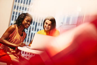 Two women discussing something over a laptop