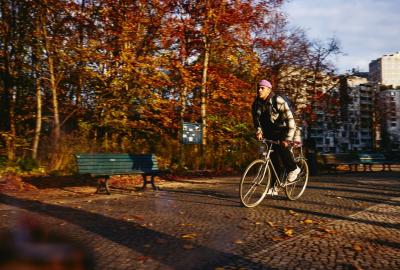 Cycling man, autumn trees and office buildings on the background.