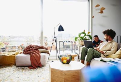 Man sitting on couch with his laptop, looking serious at a kid