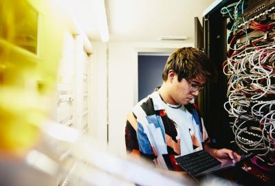 Man looking at a tablet standing in a servers room.