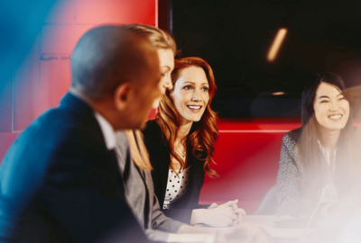 four people in business suits talking and smiling