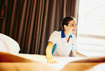 an image of a woman wearing a white polo shirt fixing some sheets in a room