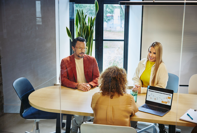 an image of three people in a meeting room discussing 