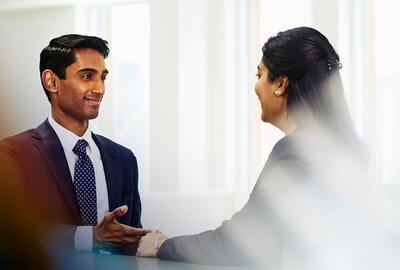 an image of a man talking to a woman while wearing a business attire