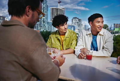 an image of colleagues in a casual attire smiling while looking to the right with skyscrapers in the background