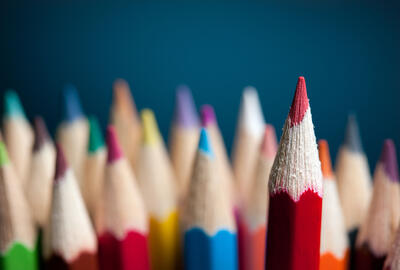 image showing a bundle of different coloured colouring pencils, with one red pencil at the forefront of the image
