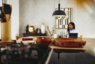 Man looking serious, sitting at a kitchen table with tablet.