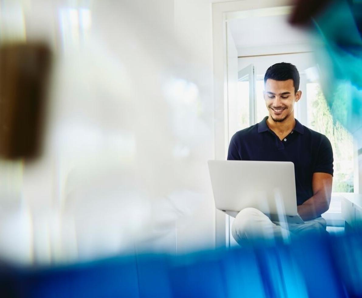 A man typing on his laptop while smiling