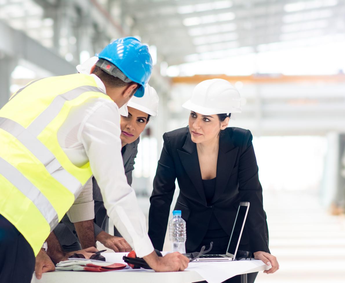 A photo of a woman wearing a hard hat working in the engineering industry