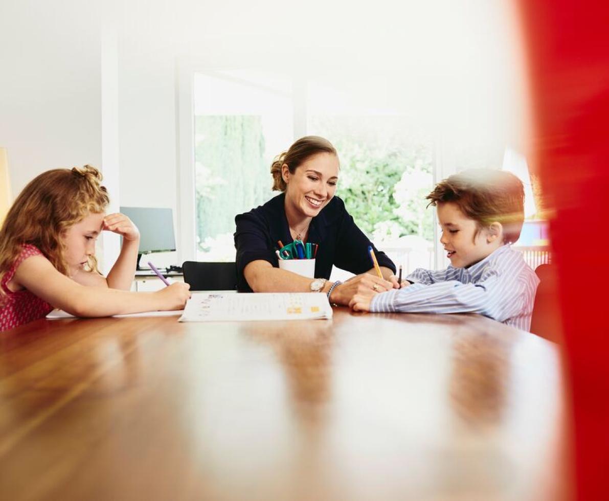 A woman working from home teaching her children